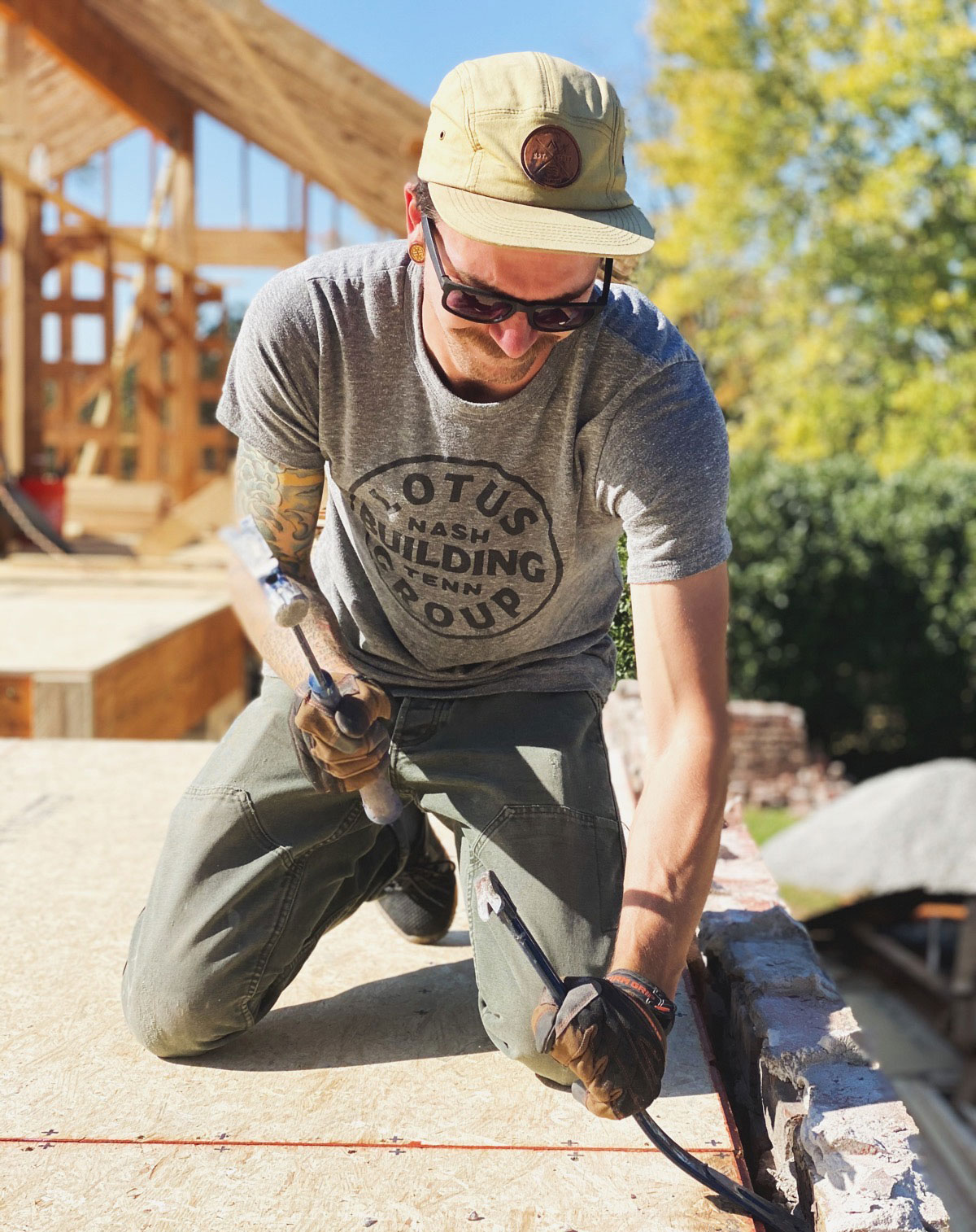 Team member of Lotus Building Group with a shirt that says "LOTUS Building Group" is on top of a roof that's being remodeled. Contact Lotus Building Group as your custom home renovation contractor in Nashville, TN.