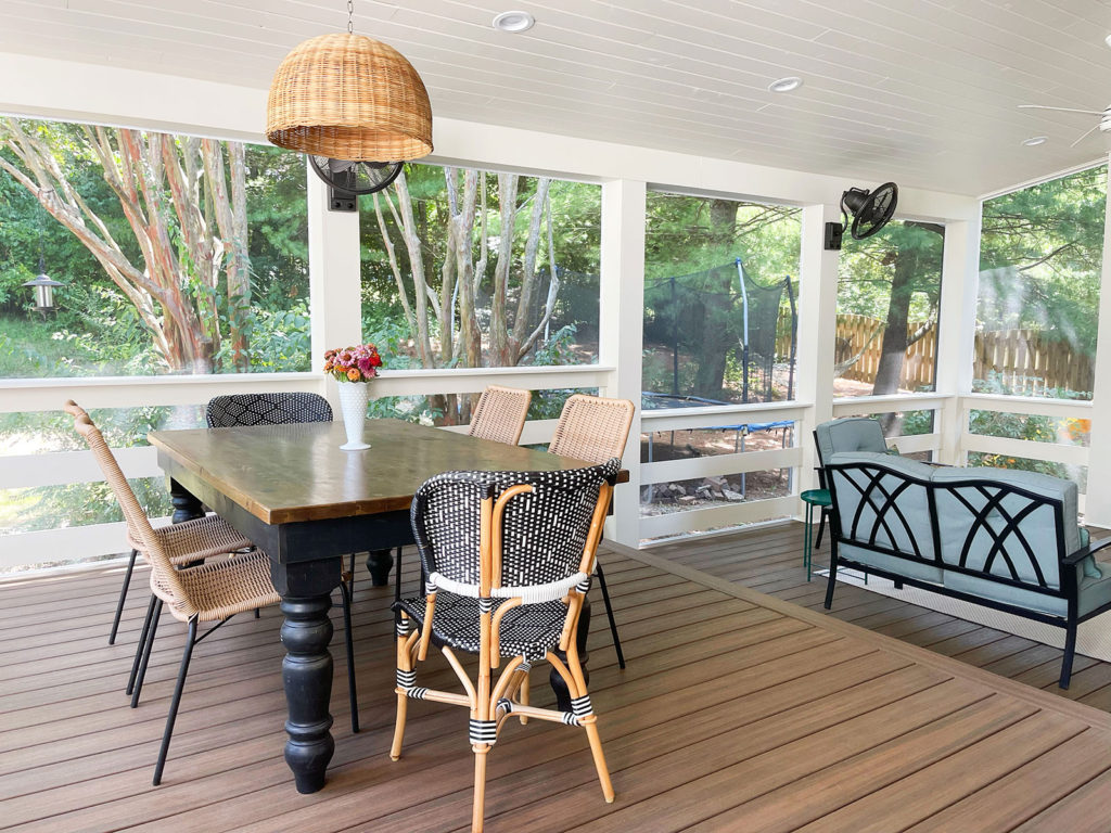 A sunroom has a tall white ceiling with a fan, white wood flooring, and a seating and dining area. The seating and doors are blue. Contact Lotus Building Group as your patio contractor in Nashville, TN. 