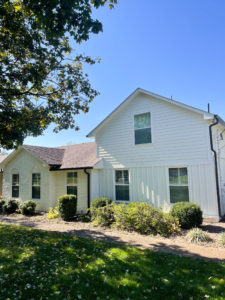 A cream colored ranch house has a new addition with two stories that's painted all white. There are bushes around the house. Contact Lotus Building Group for your new home construction projects in Nashville, TN.