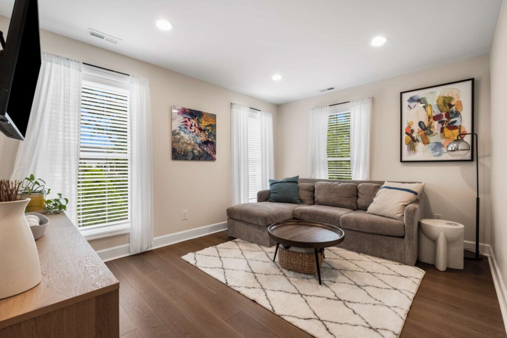 Residential home renovation project featuring a family room. This room features dark wooden flooring, white walls and grey accent furniture. Contact Lotus Building Group as your home renovation contractor in Nashville, TN.