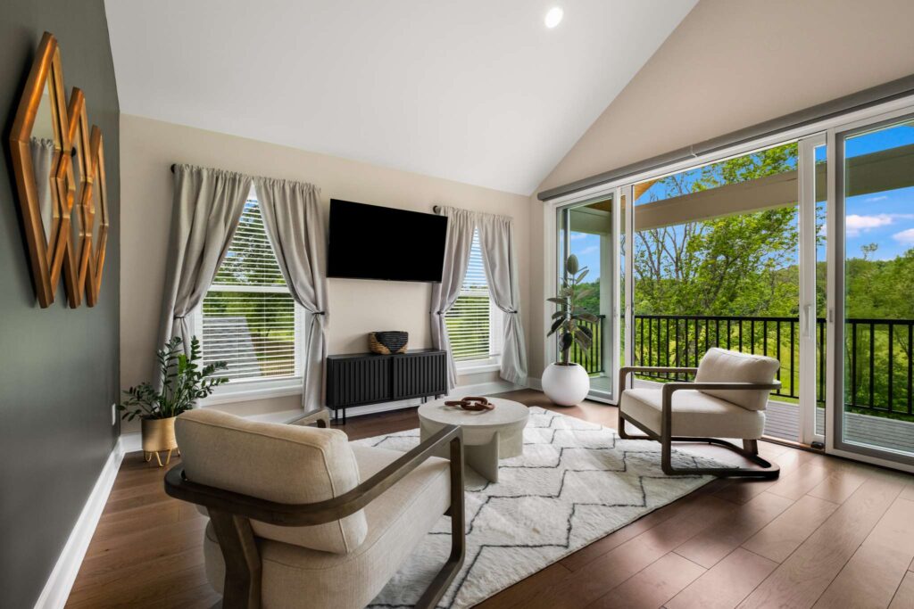 Sliding screen doors open up to a patio with a roof. There's stone and wood accents. There's seating and a flat screen TV. Contact Lotus Building Group for your new home construction projects in Nashville, TN.