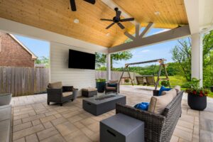Sliding screen doors open up to a patio with a roof. There's stone and wood accents. There's seating and a flat screen TV. Contact Lotus Building Group for your new home construction projects in Nashville, TN.