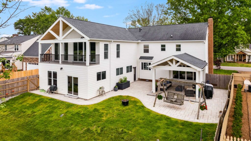 Custom build white home with balcony, patio, pergola seating, and swing in Nashville by Lotus Building Group