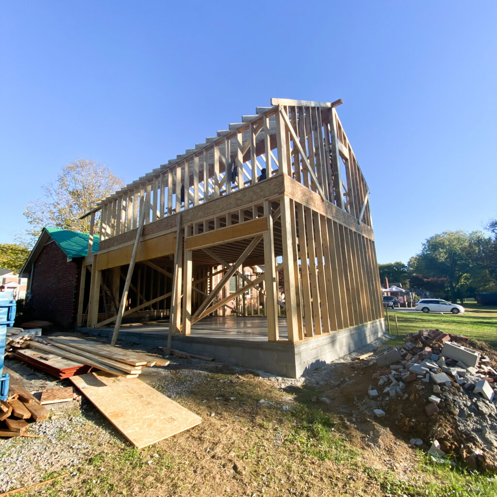 There's a wooden frame of a house that will be built. A large pile of bricks and dirt, and piles of wood, sit next to it. Contact Lotus Building Group  for your new home construction projects in Nashville, TN. 