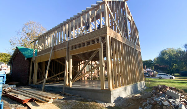 There's a wooden frame of a house that will be built. A large pile of bricks and dirt, and piles of wood, sit next to it. Contact Lotus Building Group  for your new home construction projects in Nashville, TN.
